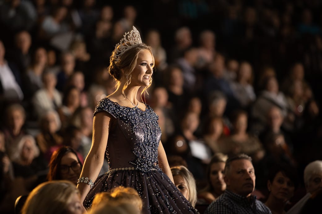 A girl wearing a crown standing in between the crowd
