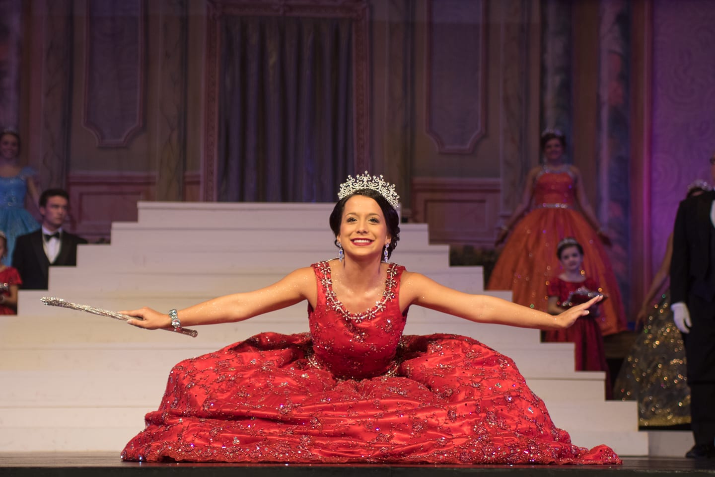 A woman in a red dress on stage with a tiara.