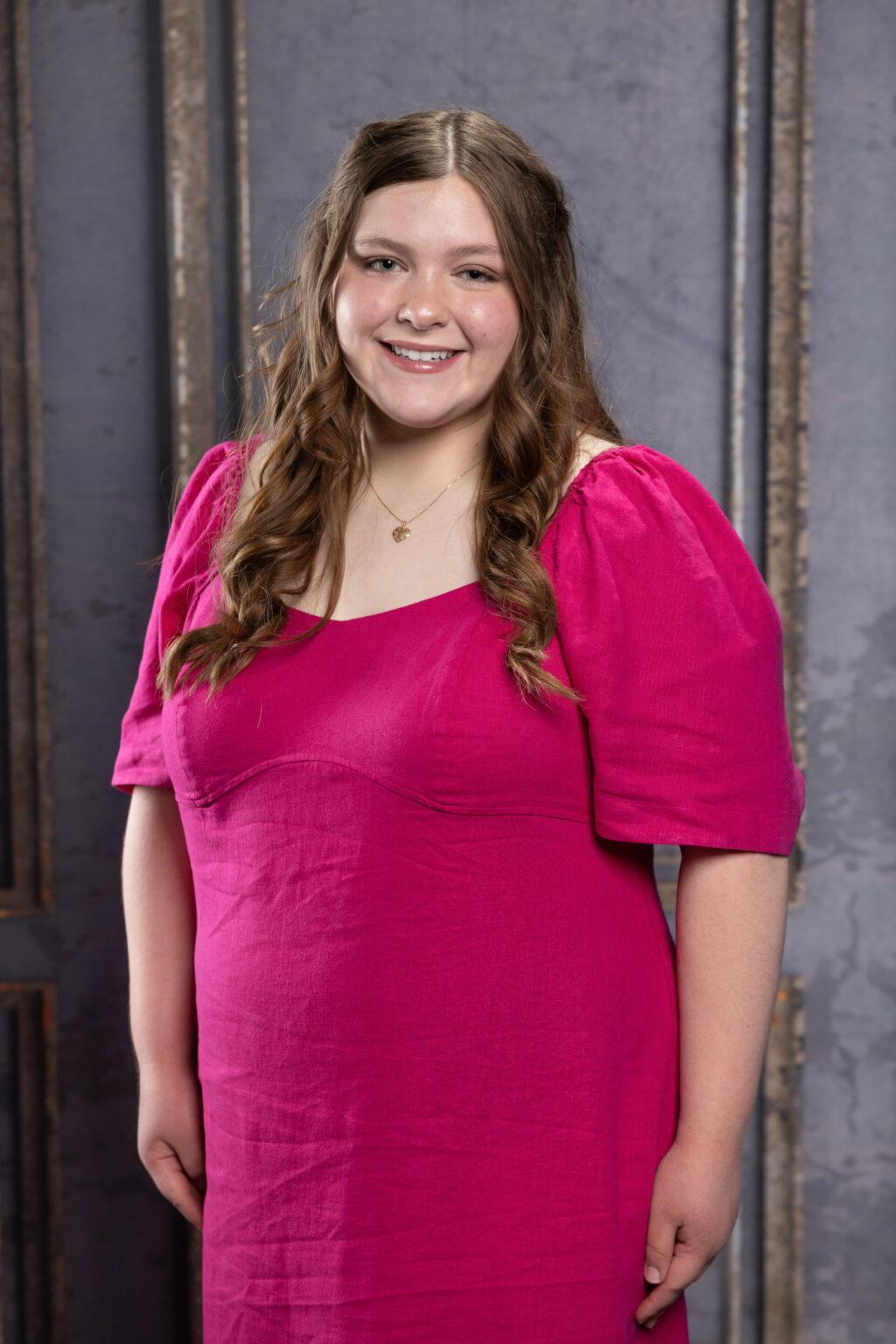 A girl wearing dark pink color designer dress, smiling at the camera