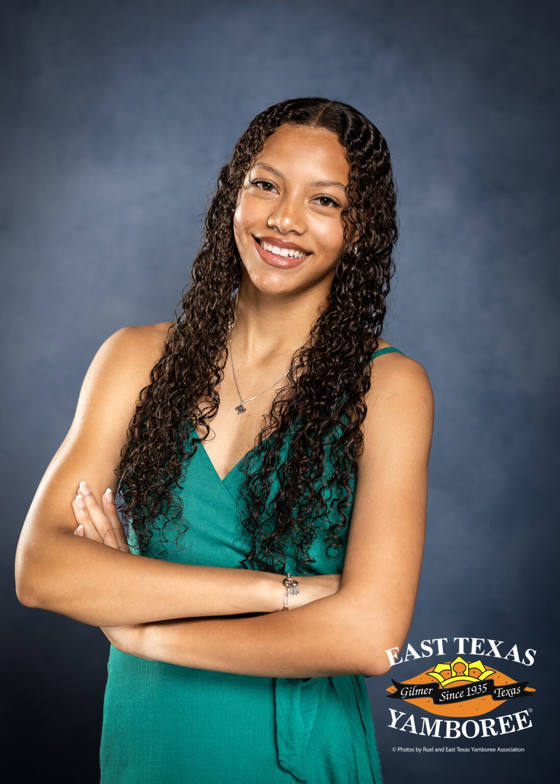 Smiling girl with curly hair and green dress.