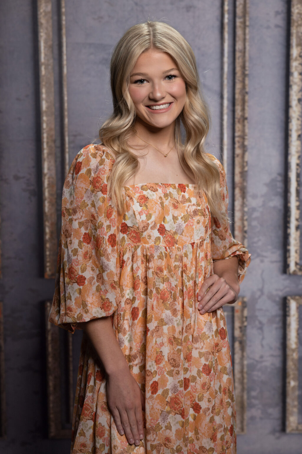 A girl wearing orange designer dress, smiling at the camera