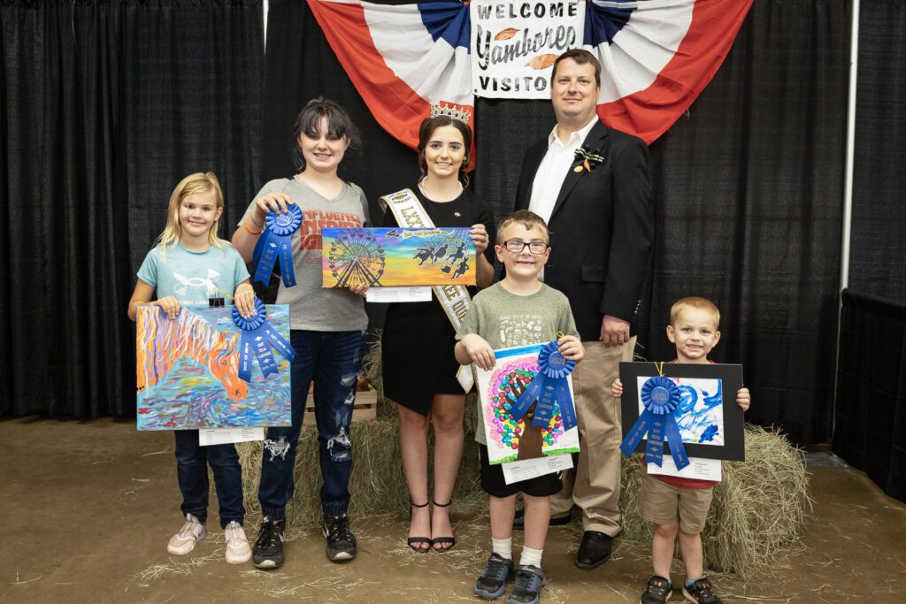 A group of people posing for a picture with their paintings.