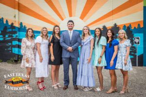 Group of people posing for a photo in front of a colorful mural with text stating "east texas yamboree".