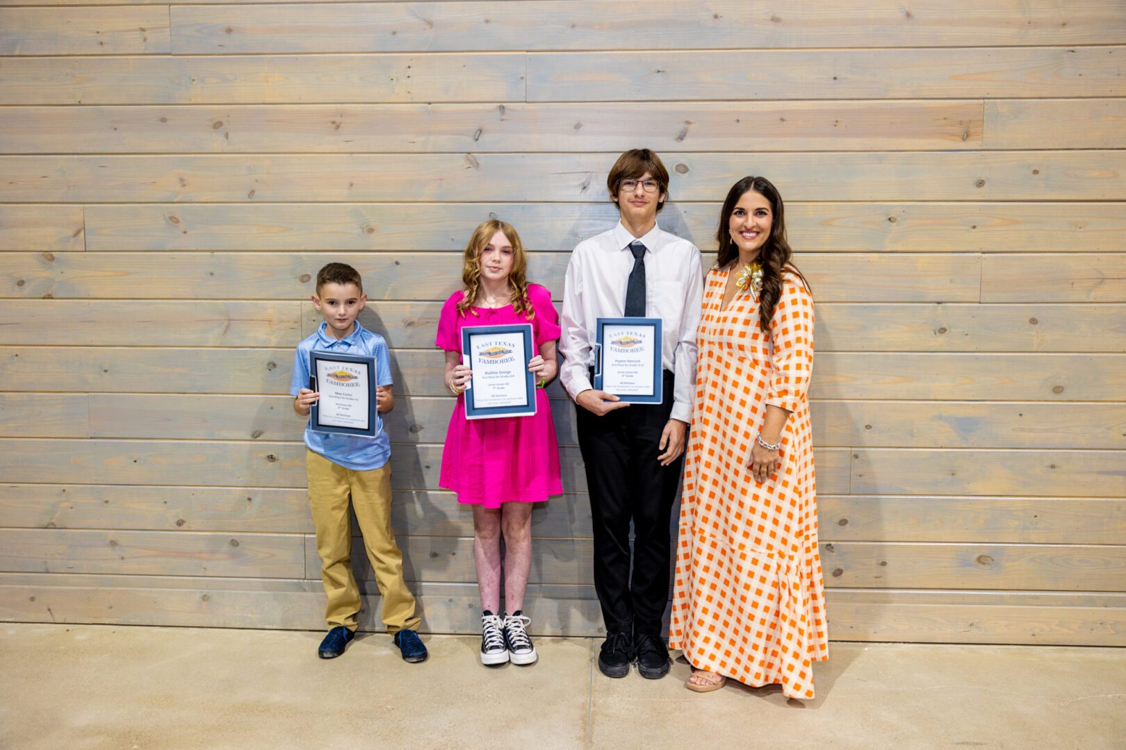 Four children pose with awards and a woman.