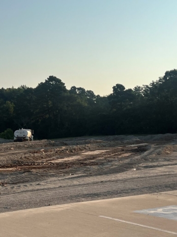 A truck in a dirt lot with trees.