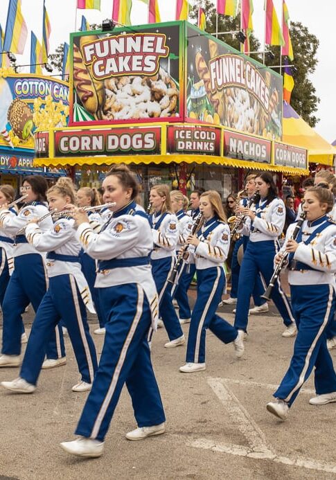 People doing parade along with band on the street